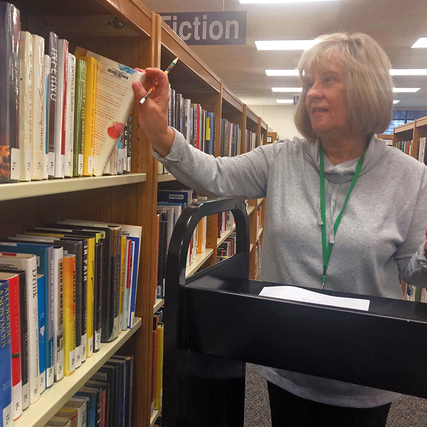 Pat Dunn pulls a book from a shelf at the Yardley-Makefield branch