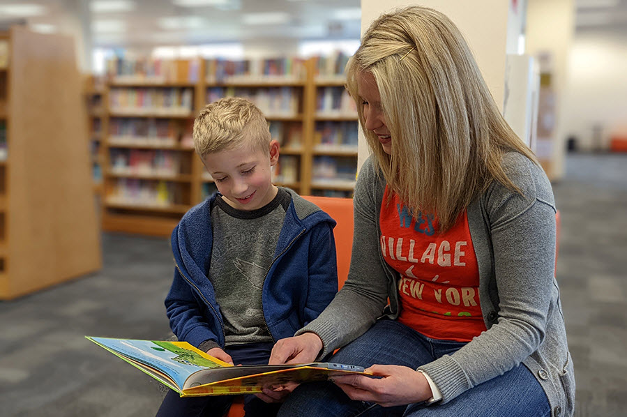 Wes and Jenn read a book together at the library