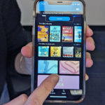 A person holds up their phone and points to the magazines tab in the cloudLibrary app