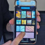 A person holds up their phone and points to the magazines tab in the cloudLibrary app
